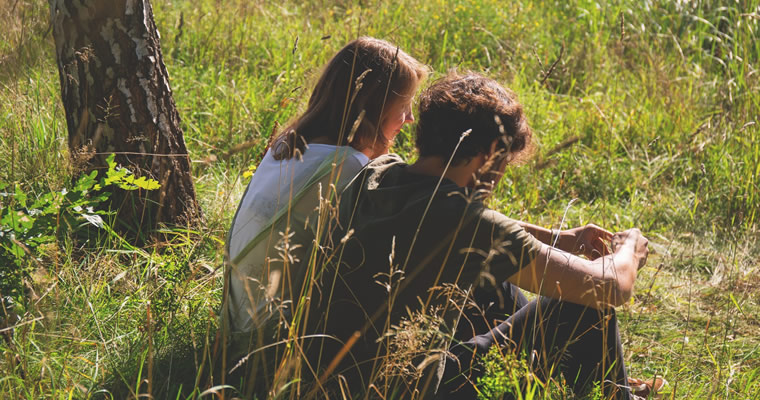 Couple sitting in meadow talking